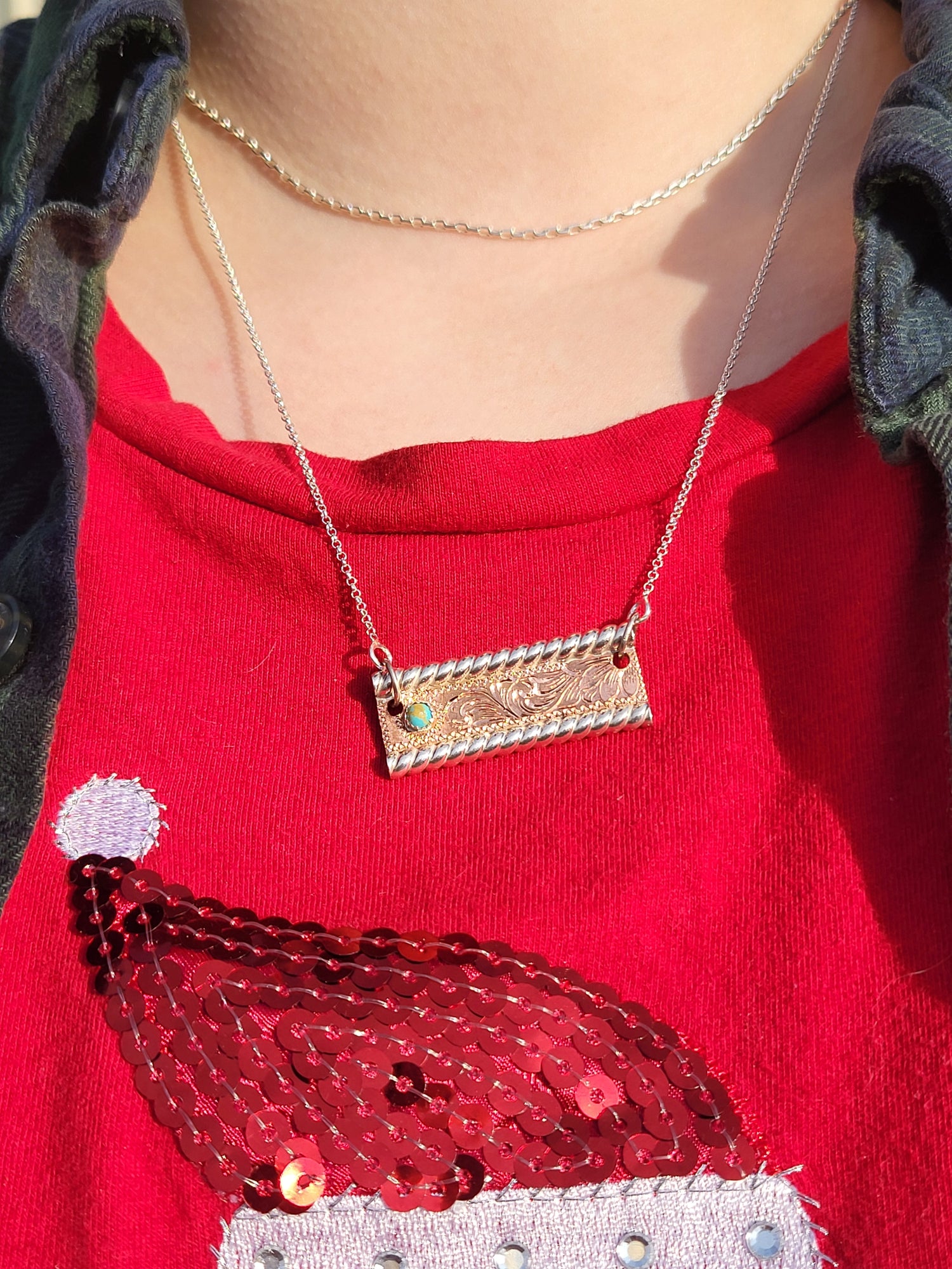 Close-up of a person wearing a red top with a decorative pendant necklace.