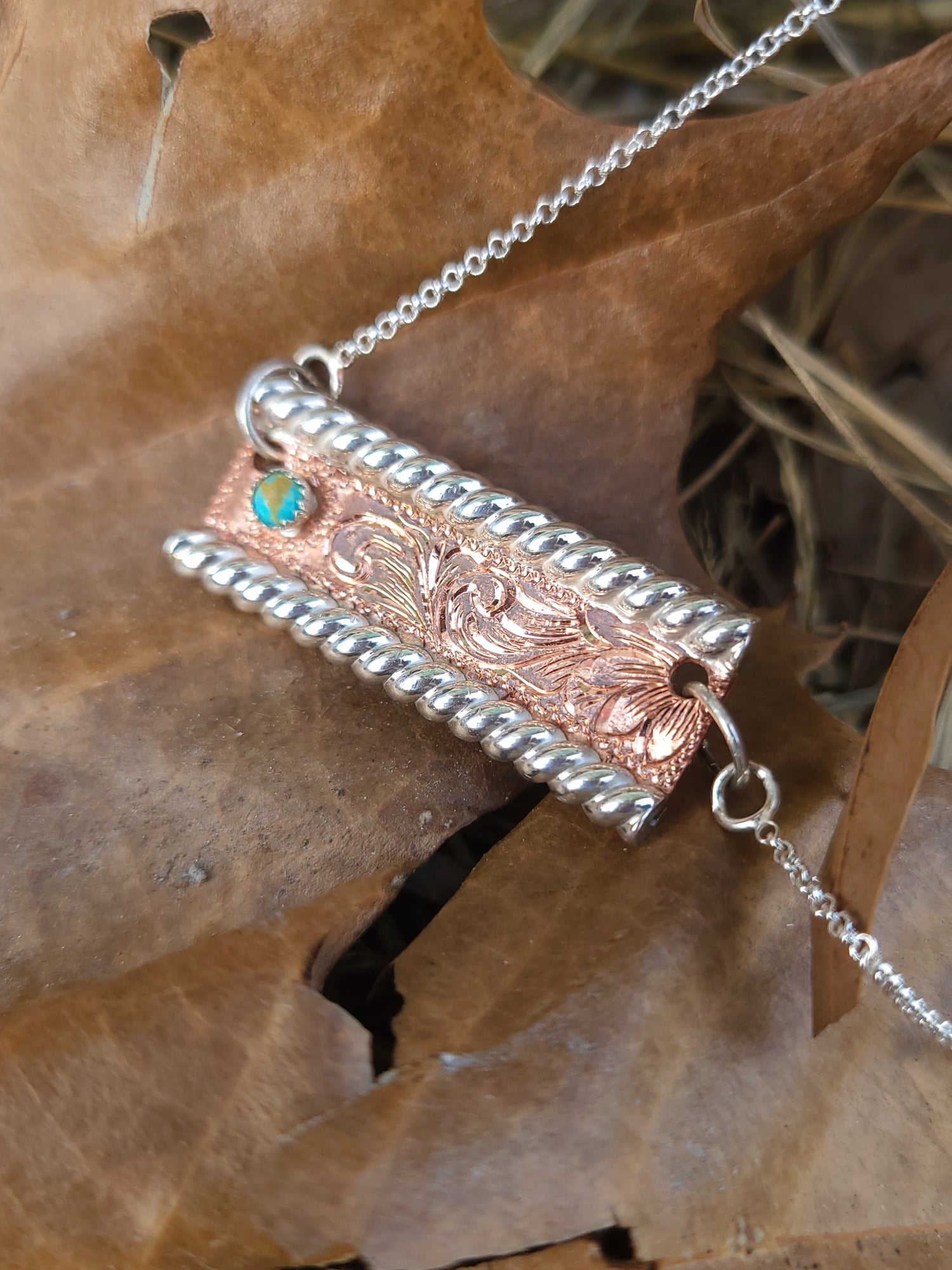 Decorative hand-engraved pendant necklace on a textured brown background