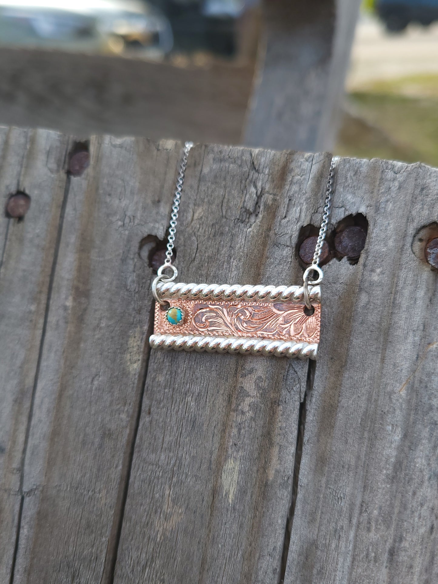 Necklace with a rectangular copper pendant on a wooden surface