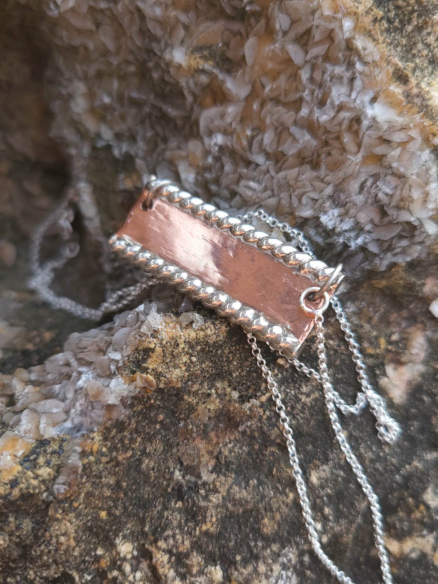 Copper pendant necklace on a textured stone background